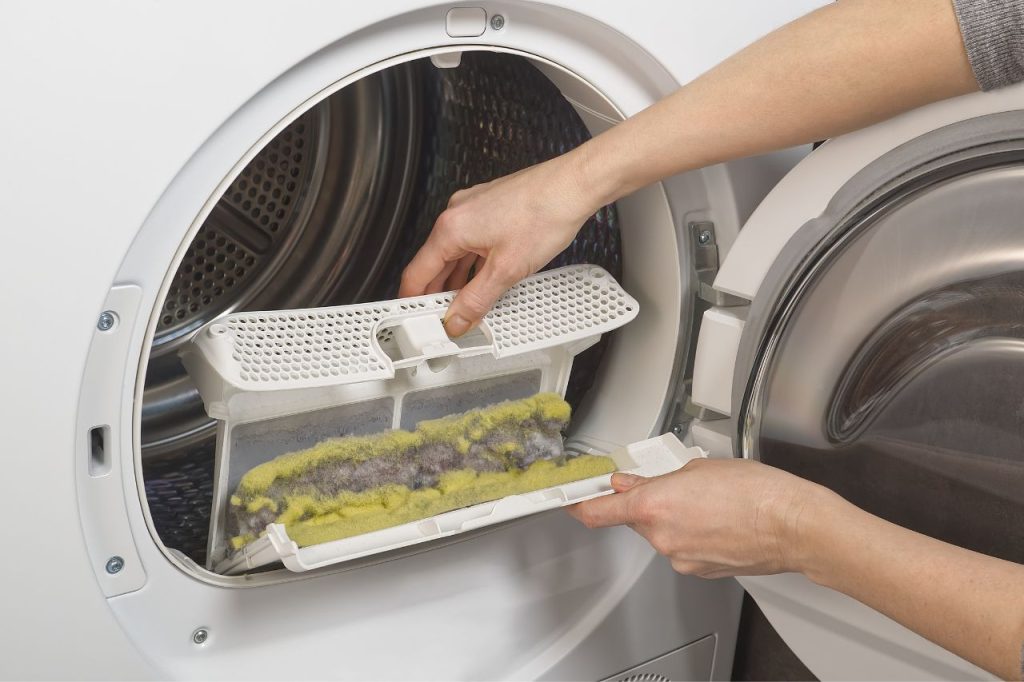 Woman removing the lint trap of a dryer inside a residential home.