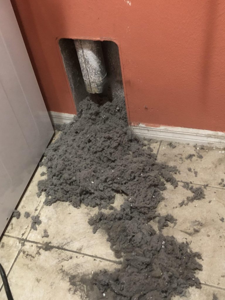 A pile of dust on the floor after a dryer vent cleaning.